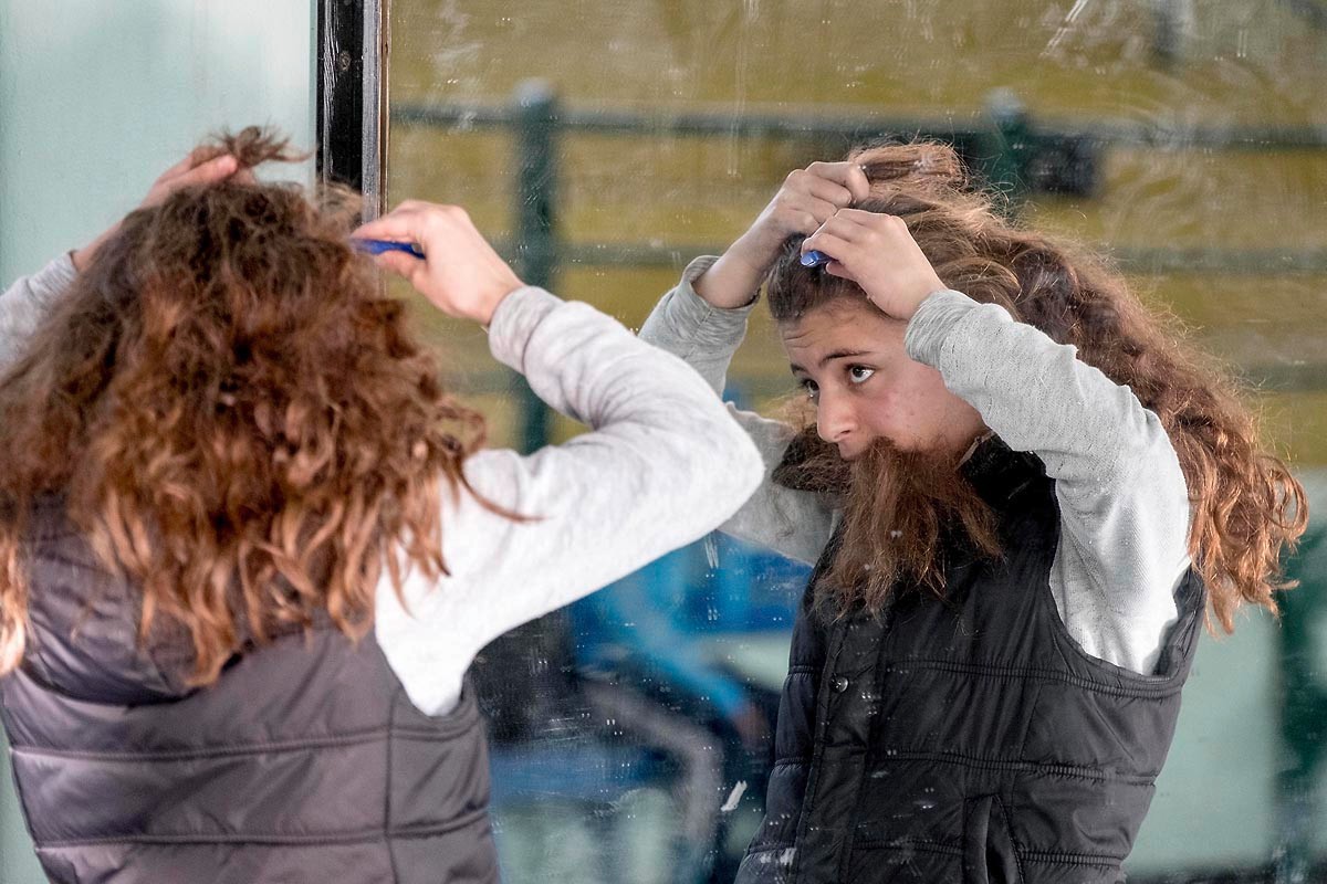Devant une vitre du gymnase, les cheveux attachés avant l'entrée sur le ring.