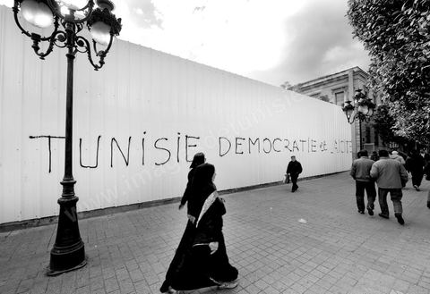 On the city walls, slogans and signs from the People's Revolution protesters are displayed in Arabic and French.