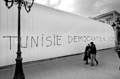On the city walls, slogans and signs from the People's Revolution protesters are displayed in Arabic and French.