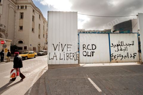 On the city walls, slogans and signs from the People's Revolution protesters are displayed in Arabic and French.