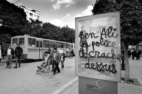 On the city walls, slogans and signs from the People's Revolution protesters are displayed in Arabic and French.