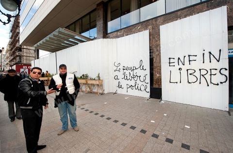 On the city walls, slogans and signs from the People's Revolution protesters are displayed in Arabic and French.
