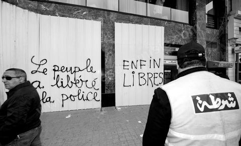 On the city walls, slogans and signs from the People's Revolution protesters are displayed in Arabic and French.