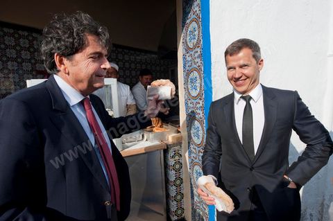 18 mars : Pierre Lellouche montre à Boris Boillon comment on prépare et mange les bombalouni au coeur du village de Sidi Bou Saïd. Après une journée de travail et de rencontres avec les membres du gouvernement tunisien, Pierre Lellouche repart sur les traces de son enfance et va faire découvrir à Boris Boillon, le nouvel ambassadeur de France, le village de Sidi Bou Saïd, son patrimoine architectural et culinaire et faire déguster les fameux Bombalouni (beignets) et thé à la menthe aux pigons du Café des Nattes. Visite de travail de Pierre Lellouche, le secrétaire d’État chargé du Commerce extérieur en Tunisie, accompagné de chefs d’entreprises. 