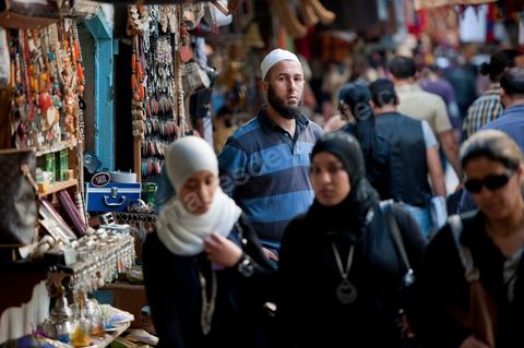 Femmes voilées de noir et homme barbu dasn les souks de la medina de Tunis le vendredi