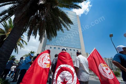 15 août 2011 : Manifestants devant le siège de l'ex RCD parti de Ben Ali. L'Union Générale Tunisienne du Travail a organisé une marche de protestation ''pour la réalisation des objectifs de la révolution et en mémoire des martyrs'' qui a débuté lundi 15 août 2011 à midi devant la bourse du travail à Tunis avant de parcourir l'avenue Mohamed V et de se disperser devant la place des droits de l'Homme.Ont participé à cette marche, les structures régionales et locales de base de l'Union, des partis politiques, des personnalités nationales, des composantes de la société civile, des intellectuels et des artistes.Les manifestants ont exprimé des revendications à caractère social et politique exigeant notamment le départ du Gouvernement de transition et de demander des comptes aux symboles de la corruption, notamment par une restitution des avoirs du peuple, spoliés par la famille du président déchu, la réforme de la Justice et l'emploi aux chômeurs.Les manifestants ont dénoncé la hausse des prix et appelé au respect des principes de la révolution et à la fidélité au sang des martyrs.La marche a été marquée par un arrêt symbolique devant le siège de l'ancien Rassemblement Constitutionnel Démocratique dissous."La Tunisie libre et les voleurs dehors", "Peuple, révolte-toi contre les restants de la dictature", "Pas de liberté, pas de retour, pour les bandes du destour" ont scandé les manifestants.