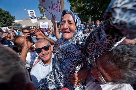 September 22: Samir’s mother, Rabia, celebrates the announcement of her son’s provisional release outside the Military Court in Tunis, where a large crowd has gathered to show support for Samir Feriani during his ongoing trial. Late in the morning, the military court decided to grant Samir Feriani provisional release despite the serious charges against him. Samir Feriani is a Tunisian police officer who has been incarcerated since late May for claiming that “Ben Ali’s criminals” were still operating within the Ministry of the Interior. Following the first hearing of his trial for “undermining state security” before the Tunis Military Court, Samir Feriani, 44, was released on provisional bail, and the trial was adjourned until September 29. This decision was met with an outpouring of joy from the dozens of family members and supporters who had gathered outside the courthouse early that morning. His family, including his three children, were in tears, and his aunt fainted. “This is a victory for human rights, for freedom of expression, and for all of Tunisia,” said Leila Feriani, the officer’s wife. September 22: Samir’s son celebrates the announcement of his father’s provisional release outside the Military Court of Tunis, where a large crowd had gathered to show support for Samir Feriani during his ongoing trial. Late in the morning, the military court decided to grant Samir Feriani provisional release despite the serious charges against him. Samir Feriani is a Tunisian police officer who has been incarcerated since late May for claiming that “Ben Ali’s criminals” were still operating within the Ministry of the Interior. At the conclusion of the first hearing of his trial for “undermining state security” before the Tunis Military Court, Samir Feriani, 44, was released on provisional bail, and the trial was adjourned until September 29. This decision was met with an outpouring of joy from dozens of relatives and supporters.