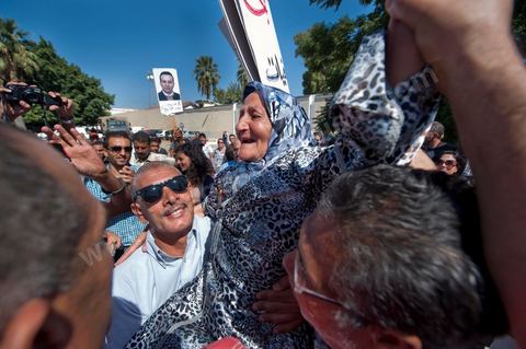 September 22: Samir’s mother, Rabia, celebrates the announcement of her son’s provisional release outside the Military Court in Tunis, where a large crowd has gathered to show support for Samir Feriani during his ongoing trial. Late in the morning, the military court decided to grant Samir Feriani provisional release despite the serious charges against him. Samir Feriani is a Tunisian police officer who has been incarcerated since late May for claiming that “Ben Ali’s criminals” were still operating within the Ministry of the Interior. Following the first hearing of his trial for “undermining state security” before the Tunis Military Court, Samir Feriani, 44, was released on provisional bail, and the trial was adjourned until September 29. This decision was met with an outpouring of joy from the dozens of family members and supporters who had gathered outside the courthouse early that morning. His family, including his three children, were in tears, and his aunt fainted. “This is a victory for human rights, for freedom of expression, and for all of Tunisia,” said Leila Feriani, the officer’s wife. September 22: Samir’s son celebrates the announcement of his father’s provisional release outside the Military Court of Tunis, where a large crowd had gathered to show support for Samir Feriani during his ongoing trial. Late in the morning, the military court decided to grant Samir Feriani provisional release despite the serious charges against him. Samir Feriani is a Tunisian police officer who has been incarcerated since late May for claiming that “Ben Ali’s criminals” were still operating within the Ministry of the Interior. At the conclusion of the first hearing of his trial for “undermining state security” before the Tunis Military Court, Samir Feriani, 44, was released on provisional bail, and the trial was adjourned until September 29. This decision was met with an outpouring of joy from dozens of relatives and supporters.