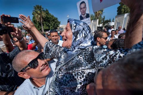 September 22: Samir’s mother, Rabia, celebrates the announcement of her son’s provisional release outside the Military Court in Tunis, where a large crowd has gathered to show support for Samir Feriani during his ongoing trial. Late in the morning, the military court decided to grant Samir Feriani provisional release despite the serious charges against him. Samir Feriani is a Tunisian police officer who has been incarcerated since late May for claiming that “Ben Ali’s criminals” were still operating within the Ministry of the Interior. Following the first hearing of his trial for “undermining state security” before the Tunis Military Court, Samir Feriani, 44, was released on provisional bail, and the trial was adjourned until September 29. This decision was met with an outpouring of joy from the dozens of family members and supporters who had gathered outside the courthouse early that morning. His family, including his three children, were in tears, and his aunt fainted. “This is a victory for human rights, for freedom of expression, and for all of Tunisia,” said Leila Feriani, the officer’s wife. September 22: Samir’s son celebrates the announcement of his father’s provisional release outside the Military Court of Tunis, where a large crowd had gathered to show support for Samir Feriani during his ongoing trial. Late in the morning, the military court decided to grant Samir Feriani provisional release despite the serious charges against him. Samir Feriani is a Tunisian police officer who has been incarcerated since late May for claiming that “Ben Ali’s criminals” were still operating within the Ministry of the Interior. At the conclusion of the first hearing of his trial for “undermining state security” before the Tunis Military Court, Samir Feriani, 44, was released on provisional bail, and the trial was adjourned until September 29. This decision was met with an outpouring of joy from dozens of relatives and supporters.