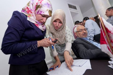 Dans le bureau Rached Ghannouchi, président et fondateur de Ennahdha, notent avec ses filles Intissar (à droite) et Yosr (à gauche) notent les  résultats provisoires lors de la soirée de résultats au QG du parti Ennahda à Tunis. 