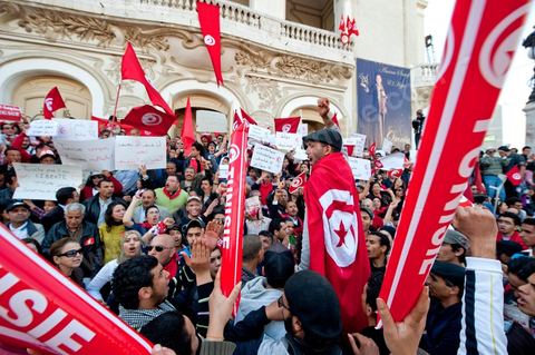 March 20, 2012: Nearly 6,000 Tunisians gathered Tuesday on Bourguiba Avenue in Tunis to celebrate Independence Day and “defend democracy” against “reactionary” forces, amid tensions fueled by the debate over identity and the role of religion.Tunisian flags were everywhere, horns blared, and the national anthem rang out: the demonstrators, who had come in response to calls on social media and from civic movements, chanted, “The people want a secular state!” “No to reactionary thinking, no to the caliphate,” or “We will not let obscurantist forces steal our revolution.”
The slogans of the revolution—“work, freedom, dignity”—were also chanted in unison. “In the name of the worker and the farmer, we continue to fight,” proclaimed one banner, while another demanded “jobs, or the government’s resignation.”  The 56th anniversary of independence—achieved on March 20, 1956, after 75 years of French protectorate rule—is taking place against a delicate backdrop, marked by growing tensions between the “Islamist” camp—which won the elections—and the “modernist” camp. The debate, exacerbated by incidents linked to Salafist radicals, centers on the question of Tunisian identity and the role religion should play in the country’s future constitution.