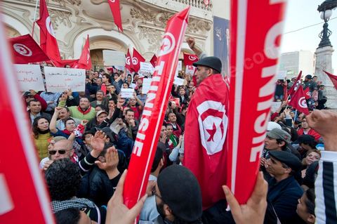 March 20, 2012: Nearly 6,000 Tunisians gathered Tuesday on Bourguiba Avenue in Tunis to celebrate Independence Day and “defend democracy” against “reactionary” forces, amid tensions fueled by the debate over identity and the role of religion.Tunisian flags were everywhere, horns blared, and the national anthem rang out: the demonstrators, who had come in response to calls on social media and from civic movements, chanted, “The people want a secular state!” “No to reactionary thinking, no to the caliphate,” or “We will not let obscurantist forces steal our revolution.”
The slogans of the revolution—“work, freedom, dignity”—were also chanted in unison. “In the name of the worker and the farmer, we continue to fight,” proclaimed one banner, while another demanded “jobs, or the government’s resignation.”  The 56th anniversary of independence—achieved on March 20, 1956, after 75 years of French protectorate rule—is taking place against a delicate backdrop, marked by growing tensions between the “Islamist” camp—which won the elections—and the “modernist” camp. The debate, exacerbated by incidents linked to Salafist radicals, centers on the question of Tunisian identity and the role religion should play in the country’s future constitution.