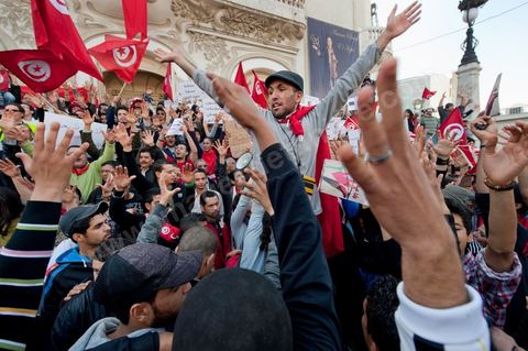 March 20, 2012: Nearly 6,000 Tunisians gathered Tuesday on Bourguiba Avenue in Tunis to celebrate Independence Day and “defend democracy” against “reactionary” forces, amid tensions fueled by the debate over identity and the role of religion.Tunisian flags were everywhere, horns blared, and the national anthem rang out: the demonstrators, who had come in response to calls on social media and from civic movements, chanted, “The people want a secular state!” “No to reactionary thinking, no to the caliphate,” or “We will not let obscurantist forces steal our revolution.”
The slogans of the revolution—“work, freedom, dignity”—were also chanted in unison. “In the name of the worker and the farmer, we continue to fight,” proclaimed one banner, while another demanded “jobs, or the government’s resignation.”  The 56th anniversary of independence—achieved on March 20, 1956, after 75 years of French protectorate rule—is taking place against a delicate backdrop, marked by growing tensions between the “Islamist” camp—which won the elections—and the “modernist” camp. The debate, exacerbated by incidents linked to Salafist radicals, centers on the question of Tunisian identity and the role religion should play in the country’s future constitution.