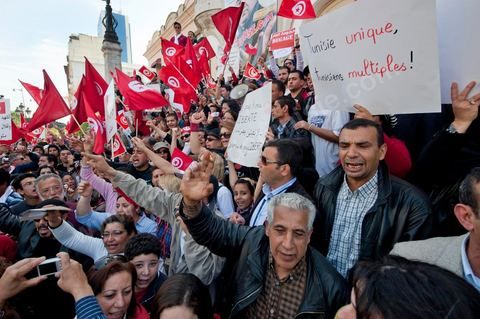 March 20, 2012: Nearly 6,000 Tunisians gathered Tuesday on Bourguiba Avenue in Tunis to celebrate Independence Day and “defend democracy” against “reactionary” forces, amid tensions fueled by the debate over identity and the role of religion.Tunisian flags were everywhere, horns blared, and the national anthem rang out: the demonstrators, who had come in response to calls on social media and from civic movements, chanted, “The people want a secular state!” “No to reactionary thinking, no to the caliphate,” or “We will not let obscurantist forces steal our revolution.”
The slogans of the revolution—“work, freedom, dignity”—were also chanted in unison. “In the name of the worker and the farmer, we continue to fight,” proclaimed one banner, while another demanded “jobs, or the government’s resignation.”  The 56th anniversary of independence—achieved on March 20, 1956, after 75 years of French protectorate rule—is taking place against a delicate backdrop, marked by growing tensions between the “Islamist” camp—which won the elections—and the “modernist” camp. The debate, exacerbated by incidents linked to Salafist radicals, centers on the question of Tunisian identity and the role religion should play in the country’s future constitution.