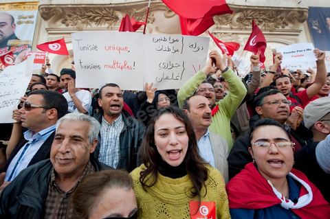 March 20, 2012: Nearly 6,000 Tunisians gathered Tuesday on Bourguiba Avenue in Tunis to celebrate Independence Day and “defend democracy” against “reactionary” forces, amid tensions fueled by the debate over identity and the role of religion.Tunisian flags were everywhere, horns blared, and the national anthem rang out: the demonstrators, who had come in response to calls on social media and from civic movements, chanted, “The people want a secular state!” “No to reactionary thinking, no to the caliphate,” or “We will not let obscurantist forces steal our revolution.”
The slogans of the revolution—“work, freedom, dignity”—were also chanted in unison. “In the name of the worker and the farmer, we continue to fight,” proclaimed one banner, while another demanded “jobs, or the government’s resignation.”  The 56th anniversary of independence—achieved on March 20, 1956, after 75 years of French protectorate rule—is taking place against a delicate backdrop, marked by growing tensions between the “Islamist” camp—which won the elections—and the “modernist” camp. The debate, exacerbated by incidents linked to Salafist radicals, centers on the question of Tunisian identity and the role religion should play in the country’s future constitution.