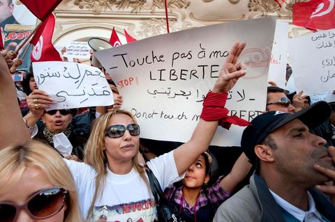 March 20, 2012: Nearly 6,000 Tunisians gathered Tuesday on Bourguiba Avenue in Tunis to celebrate Independence Day and “defend democracy” against “reactionary” forces, amid tensions fueled by the debate over identity and the role of religion.Tunisian flags were everywhere, horns blared, and the national anthem rang out: the demonstrators, who had come in response to calls on social media and from civic movements, chanted, “The people want a secular state!” “No to reactionary thinking, no to the caliphate,” or “We will not let obscurantist forces steal our revolution.”
The slogans of the revolution—“work, freedom, dignity”—were also chanted in unison. “In the name of the worker and the farmer, we continue to fight,” proclaimed one banner, while another demanded “jobs, or the government’s resignation.”  The 56th anniversary of independence—achieved on March 20, 1956, after 75 years of French protectorate rule—is taking place against a delicate backdrop, marked by growing tensions between the “Islamist” camp—which won the elections—and the “modernist” camp. The debate, exacerbated by incidents linked to Salafist radicals, centers on the question of Tunisian identity and the role religion should play in the country’s future constitution.