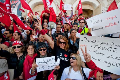 March 20, 2012: Nearly 6,000 Tunisians gathered Tuesday on Bourguiba Avenue in Tunis to celebrate Independence Day and “defend democracy” against “reactionary” forces, amid tensions fueled by the debate over identity and the role of religion.Tunisian flags were everywhere, horns blared, and the national anthem rang out: the demonstrators, who had come in response to calls on social media and from civic movements, chanted, “The people want a secular state!” “No to reactionary thinking, no to the caliphate,” or “We will not let obscurantist forces steal our revolution.”
The slogans of the revolution—“work, freedom, dignity”—were also chanted in unison. “In the name of the worker and the farmer, we continue to fight,” proclaimed one banner, while another demanded “jobs, or the government’s resignation.”  The 56th anniversary of independence—achieved on March 20, 1956, after 75 years of French protectorate rule—is taking place against a delicate backdrop, marked by growing tensions between the “Islamist” camp—which won the elections—and the “modernist” camp. The debate, exacerbated by incidents linked to Salafist radicals, centers on the question of Tunisian identity and the role religion should play in the country’s future constitution.