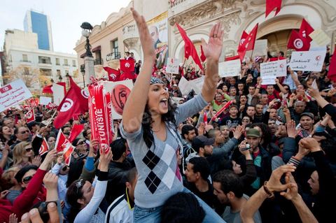 March 20, 2012: Nearly 6,000 Tunisians gathered Tuesday on Bourguiba Avenue in Tunis to celebrate Independence Day and “defend democracy” against “reactionary” forces, amid tensions fueled by the debate over identity and the role of religion.Tunisian flags were everywhere, horns blared, and the national anthem rang out: the demonstrators, who had come in response to calls on social media and from civic movements, chanted, “The people want a secular state!” “No to reactionary thinking, no to the caliphate,” or “We will not let obscurantist forces steal our revolution.”
The slogans of the revolution—“work, freedom, dignity”—were also chanted in unison. “In the name of the worker and the farmer, we continue to fight,” proclaimed one banner, while another demanded “jobs, or the government’s resignation.”  The 56th anniversary of independence—achieved on March 20, 1956, after 75 years of French protectorate rule—is taking place against a delicate backdrop, marked by growing tensions between the “Islamist” camp—which won the elections—and the “modernist” camp. The debate, exacerbated by incidents linked to Salafist radicals, centers on the question of Tunisian identity and the role religion should play in the country’s future constitution.