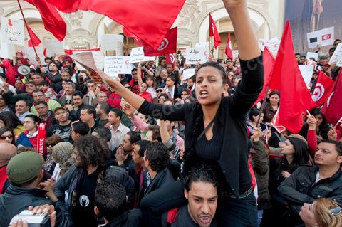 March 20, 2012: Nearly 6,000 Tunisians gathered Tuesday on Bourguiba Avenue in Tunis to celebrate Independence Day and “defend democracy” against “reactionary” forces, amid tensions fueled by the debate over identity and the role of religion.Tunisian flags were everywhere, horns blared, and the national anthem rang out: the demonstrators, who had come in response to calls on social media and from civic movements, chanted, “The people want a secular state!” “No to reactionary thinking, no to the caliphate,” or “We will not let obscurantist forces steal our revolution.”
The slogans of the revolution—“work, freedom, dignity”—were also chanted in unison. “In the name of the worker and the farmer, we continue to fight,” proclaimed one banner, while another demanded “jobs, or the government’s resignation.”  The 56th anniversary of independence—achieved on March 20, 1956, after 75 years of French protectorate rule—is taking place against a delicate backdrop, marked by growing tensions between the “Islamist” camp—which won the elections—and the “modernist” camp. The debate, exacerbated by incidents linked to Salafist radicals, centers on the question of Tunisian identity and the role religion should play in the country’s future constitution.