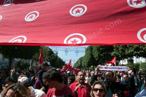 March 20, 2012: Nearly 6,000 Tunisians gathered Tuesday on Bourguiba Avenue in Tunis to celebrate Independence Day and “defend democracy” against “reactionary” forces, amid tensions fueled by the debate over identity and the role of religion.Tunisian flags were everywhere, horns blared, and the national anthem rang out: the demonstrators, who had come in response to calls on social media and from civic movements, chanted, “The people want a secular state!” “No to reactionary thinking, no to the caliphate,” or “We will not let obscurantist forces steal our revolution.”
The slogans of the revolution—“work, freedom, dignity”—were also chanted in unison. “In the name of the worker and the farmer, we continue to fight,” proclaimed one banner, while another demanded “jobs, or the government’s resignation.”  The 56th anniversary of independence—achieved on March 20, 1956, after 75 years of French protectorate rule—is taking place against a delicate backdrop, marked by growing tensions between the “Islamist” camp—which won the elections—and the “modernist” camp. The debate, exacerbated by incidents linked to Salafist radicals, centers on the question of Tunisian identity and the role religion should play in the country’s future constitution.