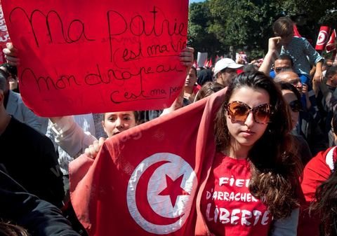 March 20, 2012: Nearly 6,000 Tunisians gathered Tuesday on Bourguiba Avenue in Tunis to celebrate Independence Day and “defend democracy” against “reactionary” forces, amid tensions fueled by the debate over identity and the role of religion.Tunisian flags were everywhere, horns blared, and the national anthem rang out: the demonstrators, who had come in response to calls on social media and from civic movements, chanted, “The people want a secular state!” “No to reactionary thinking, no to the caliphate,” or “We will not let obscurantist forces steal our revolution.”
The slogans of the revolution—“work, freedom, dignity”—were also chanted in unison. “In the name of the worker and the farmer, we continue to fight,” proclaimed one banner, while another demanded “jobs, or the government’s resignation.”  The 56th anniversary of independence—achieved on March 20, 1956, after 75 years of French protectorate rule—is taking place against a delicate backdrop, marked by growing tensions between the “Islamist” camp—which won the elections—and the “modernist” camp. The debate, exacerbated by incidents linked to Salafist radicals, centers on the question of Tunisian identity and the role religion should play in the country’s future constitution.
