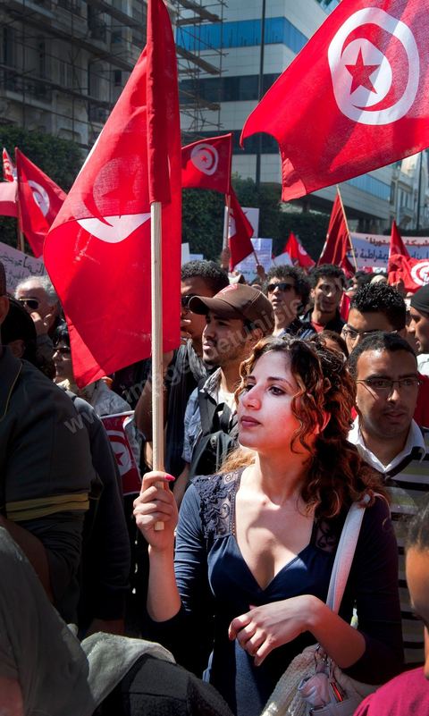 March 20, 2012: Nearly 6,000 Tunisians gathered Tuesday on Bourguiba Avenue in Tunis to celebrate Independence Day and “defend democracy” against “reactionary” forces, amid tensions fueled by the debate over identity and the role of religion.Tunisian flags were everywhere, horns blared, and the national anthem rang out: the demonstrators, who had come in response to calls on social media and from civic movements, chanted, “The people want a secular state!” “No to reactionary thinking, no to the caliphate,” or “We will not let obscurantist forces steal our revolution.”
The slogans of the revolution—“work, freedom, dignity”—were also chanted in unison. “In the name of the worker and the farmer, we continue to fight,” proclaimed one banner, while another demanded “jobs, or the government’s resignation.”  The 56th anniversary of independence—achieved on March 20, 1956, after 75 years of French protectorate rule—is taking place against a delicate backdrop, marked by growing tensions between the “Islamist” camp—which won the elections—and the “modernist” camp. The debate, exacerbated by incidents linked to Salafist radicals, centers on the question of Tunisian identity and the role religion should play in the country’s future constitution.