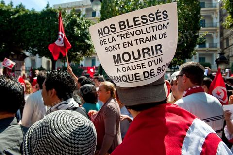 March 20, 2012: Nearly 6,000 Tunisians gathered Tuesday on Bourguiba Avenue in Tunis to celebrate Independence Day and “defend democracy” against “reactionary” forces, amid tensions fueled by the debate over identity and the role of religion.Tunisian flags were everywhere, horns blared, and the national anthem rang out: the demonstrators, who had come in response to calls on social media and from civic movements, chanted, “The people want a secular state!” “No to reactionary thinking, no to the caliphate,” or “We will not let obscurantist forces steal our revolution.”
The slogans of the revolution—“work, freedom, dignity”—were also chanted in unison. “In the name of the worker and the farmer, we continue to fight,” proclaimed one banner, while another demanded “jobs, or the government’s resignation.”  The 56th anniversary of independence—achieved on March 20, 1956, after 75 years of French protectorate rule—is taking place against a delicate backdrop, marked by growing tensions between the “Islamist” camp—which won the elections—and the “modernist” camp. The debate, exacerbated by incidents linked to Salafist radicals, centers on the question of Tunisian identity and the role religion should play in the country’s future constitution.