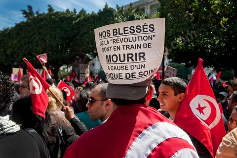 March 20, 2012: Nearly 6,000 Tunisians gathered Tuesday on Bourguiba Avenue in Tunis to celebrate Independence Day and “defend democracy” against “reactionary” forces, amid tensions fueled by the debate over identity and the role of religion.Tunisian flags were everywhere, horns blared, and the national anthem rang out: the demonstrators, who had come in response to calls on social media and from civic movements, chanted, “The people want a secular state!” “No to reactionary thinking, no to the caliphate,” or “We will not let obscurantist forces steal our revolution.”
The slogans of the revolution—“work, freedom, dignity”—were also chanted in unison. “In the name of the worker and the farmer, we continue to fight,” proclaimed one banner, while another demanded “jobs, or the government’s resignation.”  The 56th anniversary of independence—achieved on March 20, 1956, after 75 years of French protectorate rule—is taking place against a delicate backdrop, marked by growing tensions between the “Islamist” camp—which won the elections—and the “modernist” camp. The debate, exacerbated by incidents linked to Salafist radicals, centers on the question of Tunisian identity and the role religion should play in the country’s future constitution.