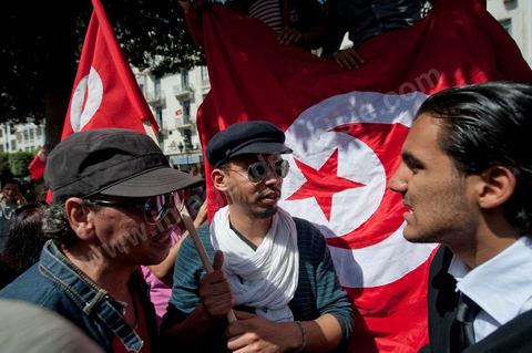 March 20, 2012: Nearly 6,000 Tunisians gathered Tuesday on Bourguiba Avenue in Tunis to celebrate Independence Day and “defend democracy” against “reactionary” forces, amid tensions fueled by the debate over identity and the role of religion.Tunisian flags were everywhere, horns blared, and the national anthem rang out: the demonstrators, who had come in response to calls on social media and from civic movements, chanted, “The people want a secular state!” “No to reactionary thinking, no to the caliphate,” or “We will not let obscurantist forces steal our revolution.”
The slogans of the revolution—“work, freedom, dignity”—were also chanted in unison. “In the name of the worker and the farmer, we continue to fight,” proclaimed one banner, while another demanded “jobs, or the government’s resignation.”  The 56th anniversary of independence—achieved on March 20, 1956, after 75 years of French protectorate rule—is taking place against a delicate backdrop, marked by growing tensions between the “Islamist” camp—which won the elections—and the “modernist” camp. The debate, exacerbated by incidents linked to Salafist radicals, centers on the question of Tunisian identity and the role religion should play in the country’s future constitution.