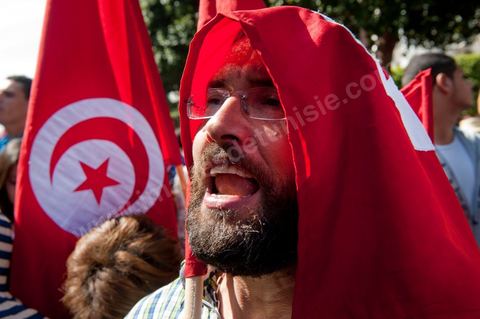 March 20, 2012: Nearly 6,000 Tunisians gathered Tuesday on Bourguiba Avenue in Tunis to celebrate Independence Day and “defend democracy” against “reactionary” forces, amid tensions fueled by the debate over identity and the role of religion.Tunisian flags were everywhere, horns blared, and the national anthem rang out: the demonstrators, who had come in response to calls on social media and from civic movements, chanted, “The people want a secular state!” “No to reactionary thinking, no to the caliphate,” or “We will not let obscurantist forces steal our revolution.”
The slogans of the revolution—“work, freedom, dignity”—were also chanted in unison. “In the name of the worker and the farmer, we continue to fight,” proclaimed one banner, while another demanded “jobs, or the government’s resignation.”  The 56th anniversary of independence—achieved on March 20, 1956, after 75 years of French protectorate rule—is taking place against a delicate backdrop, marked by growing tensions between the “Islamist” camp—which won the elections—and the “modernist” camp. The debate, exacerbated by incidents linked to Salafist radicals, centers on the question of Tunisian identity and the role religion should play in the country’s future constitution.
