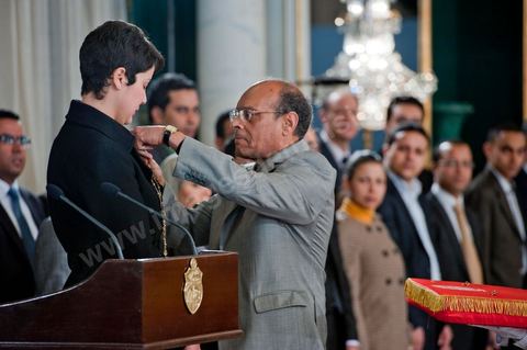 March 12: Moncef Marzouki pinned a Tunisian flag pin on young student Khaoula Rchidi at the Presidential Palace in Carthage; the President of the Republic presided over a Tunisian flag-raising ceremony. During the ceremony, Moncef Marzouki awarded a decoration to student Khaoula Rchidi and issued a message to anyone who desecrates the flag, “a symbol of a Muslim people.” Last week was marked by incidents that took place at the University of Mannouba. The young student, Khaoula Rchidi, who was awarded the Order of the Republic, was moved: “I didn’t think twice; I saw what he was doing and reacted immediately. I’m from Gafsa and I’m hot-blooded. Maybe that’s why I stepped in. Our flag is precious; we must not take it for granted.” After the speech, the national anthem was sung with great emotion by those present. Khaoula Rchidi was then welcomed into the Golden Room and honored by the president: “What she did was exceptional; she defended Tunisia. It was moral strength against physical force,” he acknowledged. Amel Aloui, a student and member of the UGET who was assaulted during the incidents at the Mannouba Faculty, also met with Moncef Marzouki and was applauded by those present.

