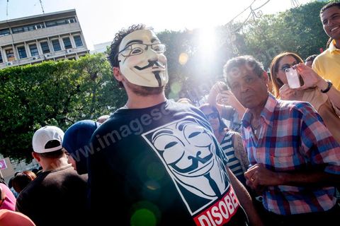 22 octobre 2012 : Un jeune activiste avec un masque de Anonymous devant le Ministère de l'Intérieur. Plus de 3000 personnes se sont rassemblées lundi sans incident à l'avenue Habib Bourguiba de Tunis pour dénoncer les violences politiques et une dérive autoritaire du pouvoir dominé par les islamistes, quelques jours après la mort d'un opposant politique. A l'apel de la troika de l'oppostion Nidaa Tounes, Al Jomhouri et Al Massar, les slogans criés dénoncent l’extrémisme et la violence politique, synonymes de terrorisme et de dictature et appellent à la dissolution des comités de protection de la Révolution, responsables, selon eux, de l’assassinat de Lotfi Nagdh, coordinateur de Nida Tounes à Tataouine, le 18 octobre. D’ailleurs, un portrait du disparu est brandi par les manifestants.