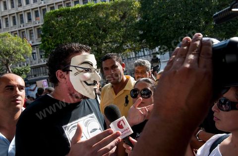 22 octobre 2012 : Un jeune activiste avec un masque de Anonymous devant le Ministère de l'Intérieur. Plus de 3000 personnes se sont rassemblées lundi sans incident à l'avenue Habib Bourguiba de Tunis pour dénoncer les violences politiques et une dérive autoritaire du pouvoir dominé par les islamistes, quelques jours après la mort d'un opposant politique. A l'apel de la troika de l'oppostion Nidaa Tounes, Al Jomhouri et Al Massar, les slogans criés dénoncent l’extrémisme et la violence politique, synonymes de terrorisme et de dictature et appellent à la dissolution des comités de protection de la Révolution, responsables, selon eux, de l’assassinat de Lotfi Nagdh, coordinateur de Nida Tounes à Tataouine, le 18 octobre. D’ailleurs, un portrait du disparu est brandi par les manifestants.