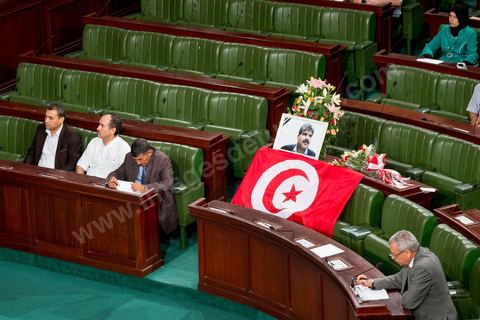 06 août 2013 : en place du siège du député assassiné  Mohamed Brahmi, des gerbes, son portrait et un drapeau national à la première séance de l'Assemblée depuis l'assassinat du député Mohamed Brahmi. La séance plénière débute par un long hommage au martyr avec prières et discours en présence des députés, hormis les 57 en retrait, du Premier Ministre et des ministres de l'Intérieur et de la Défense qui par leurs discours exposeront la situation dans le pays.