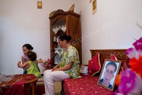 In the living room with her two daughters and a portrait of her missing husband. At Omelkhir Ouiretani’s home, this young mother of two daughters is searching for her husband, Nabil, who went missing on the boat on March 29, 2011, in the Kabaria neighborhood.