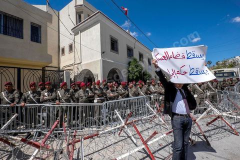 A man carries a placard which reads in Arabic, "Down with military justice, down with police rule" during a gathering on April 16, 2014, in front to National Constituent Assembly in the capital Tunis to protest against lenient verdicts by a military court against former officials of the regime of Ben Ali in the case of protesters killed and injured during the revolution. 
