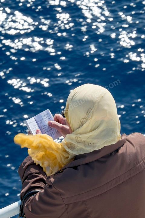 22 au juin 2014 : femme lisant le Coran. passagers sur le pont à l'approche de la Tunisie à bord du nouveau navire Tanit de la CTN (Compagnie Tunisienne de Navigation) aller-retour Tunis-Marseille. Le retour des immigrés tunisiens en France chaque été représente une manne touristique et financière très importante pour la Tunisie. Le navire Tanit a été mis en service en 2012, il mesure 212 m de long pour 30 m de large, peut atteindre la vitesse max de 27,5 noeuds, capacité d'accueil 3200 passagers et 1060 véhicules.
