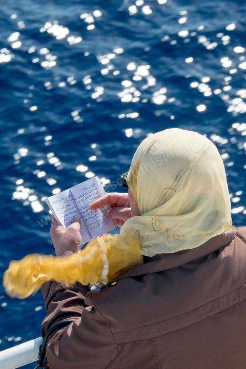 22 au juin 2014 : femme lisant le Coran. passagers sur le pont à l'approche de la Tunisie à bord du nouveau navire Tanit de la CTN (Compagnie Tunisienne de Navigation) aller-retour Tunis-Marseille. Le retour des immigrés tunisiens en France chaque été représente une manne touristique et financière très importante pour la Tunisie. Le navire Tanit a été mis en service en 2012, il mesure 212 m de long pour 30 m de large, peut atteindre la vitesse max de 27,5 noeuds, capacité d'accueil 3200 passagers et 1060 véhicules.