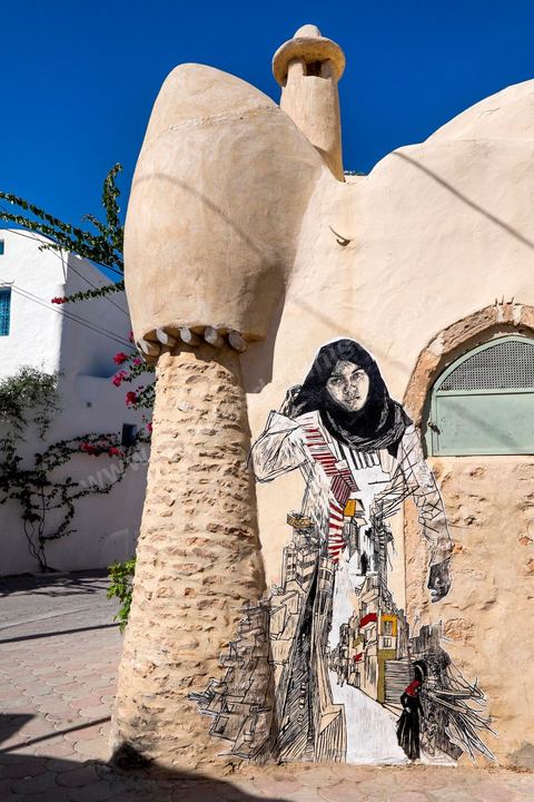 Oeuvres de l'artiste américain SWOON pour le Projet DjerbaHood : après la Tour Paris 13, la team Itinerrance dépose ses valises dans un village traditionnel de l’île de Djerba, Erriadh. Depuis le début du mois de juillet, le village d’Erriadh se métamorphose petit à petit pour devenir un véritable musée à ciel ouvert. Une sélection d’artistes des quatre coins du monde ont été invités à s’exprimer dans ce décor unique à l’architecture authentique : murs blancs, portes bleues turquoises, dômes, veilles constructions et divers lieux abandonnés, autant de possibilités qui donneront naissance à des créations uniques aux couleurs locales.