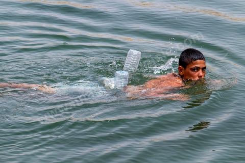 Anouar (17 ans) et Bilel (15 ans) vienent régulièrement depuis juillet se baigner dans lac de "Gafsa Beach". Ils viennent en stop de Moulares à une vingtaine de km du lac. Bilel a confectionné une bouée grâce à deux bouteille en plastique attachée à son short.