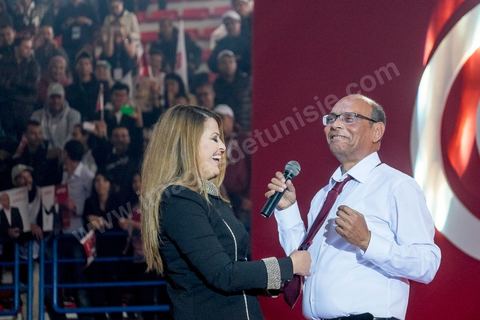 14 décembre 2014 : Au milieu de son speech, deux jeunes femmes sont arrivées sur le podium en ramenant un cadeau au candidat au second tour de l’élection présidentielle une cravate rouge ! Connu pour avoir toujours refusé de porter de cravate, afin de ne pas rompre son élan populiste, Moncef Marzouki a accepté le cadeau des deux jeunes filles et l’a même porté sur le champ. Grand meeting de Moncef Marzouki qui fait salle comble à la coupole de Tunis à une semaine du 2d tour des élections présidentielles. Moncef Marzouki, a appelé ses partisans, « à ne pas tomber dans le piège des insultes et à ne pas dire du mal de son rival Béji Caid Essebsi », tout en affirmant «nous avons le droit de juger cet homme pour son passé et pour son rôle destructeur au cours de la phase transitoire…, mais notre combat est celui des valeurs et l’éthique».Le président sortant et candidat au second tour de la présidentielle a tenu dimanche un meeting au palais des sports d’El Menzah. Ses partisans venus des différentes régions du pays ont scandé des slogans hostiles à son rival Béji Caid Essebsi et à son parti Nidaa Tounes.