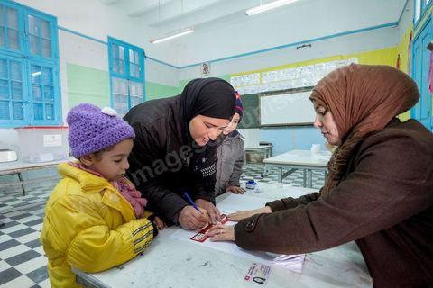 21 décembre 2014 : Accompagnée de ses enfants, une habitante accomplit son devoir civique. jour de vote pour le second tour des élections présidentielles opposant Beji Caid Essebsi, favori,  au président sortant Moncef Marzouki.