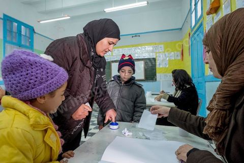 21 décembre 2014 : Accompagnée de ses enfants, une habitante accomplit son devoir civique. jour de vote pour le second tour des élections présidentielles opposant Beji Caid Essebsi, favori,  au président sortant Moncef Marzouki.
