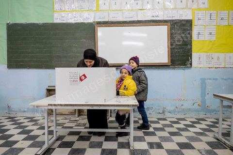 21 décembre 2014 : Accompagnée de ses enfants, une habitante accomplit son devoir civique. jour de vote pour le second tour des élections présidentielles opposant Beji Caid Essebsi, favori,  au président sortant Moncef Marzouki.