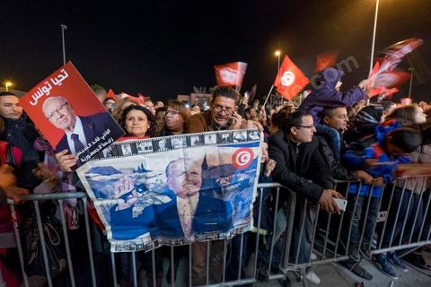 21 décembre 2014 : Militant avec portrait historique de Habib Bourguiba et de Béji Caid Essebsi. Dès la fin du scrutin à 18h, les rumeurs d'une large victoire de Beji Caïd Essebsi, candidat du parti Nidaa Tounes, circulent. Avec 8 à 10 points d'avance selon les sondages, Béji Caid Essebsi remporte les 1ères élections présidentielles libres en Tunisie depuis la révolution de 2011. A cette annonce les militants sont venus nombreux féter la victoire annoncée devant le QG de campagne du parti dans le quartier très huppé des Berges du Lac de Tunis.