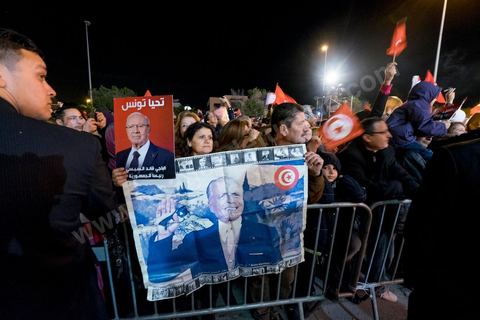 21 décembre 2014 : Militant avec portrait historique de Habib Bourguiba et de Béji Caid Essebsi. Dès la fin du scrutin à 18h, les rumeurs d'une large victoire de Beji Caïd Essebsi, candidat du parti Nidaa Tounes, circulent. Avec 8 à 10 points d'avance selon les sondages, Béji Caid Essebsi remporte les 1ères élections présidentielles libres en Tunisie depuis la révolution de 2011. A cette annonce les militants sont venus nombreux féter la victoire annoncée devant le QG de campagne du parti dans le quartier très huppé des Berges du Lac de Tunis.