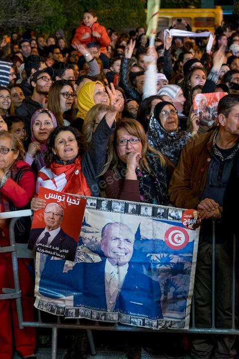 21 décembre 2014 : Militant avec portrait historique de Habib Bourguiba et de Béji Caid Essebsi. Dès la fin du scrutin à 18h, les rumeurs d'une large victoire de Beji Caïd Essebsi, candidat du parti Nidaa Tounes, circulent. Avec 8 à 10 points d'avance selon les sondages, Béji Caid Essebsi remporte les 1ères élections présidentielles libres en Tunisie depuis la révolution de 2011. A cette annonce les militants sont venus nombreux féter la victoire annoncée devant le QG de campagne du parti dans le quartier très huppé des Berges du Lac de Tunis.