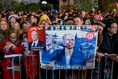21 décembre 2014 : Militant avec portrait historique de Habib Bourguiba et de Béji Caid Essebsi. Dès la fin du scrutin à 18h, les rumeurs d'une large victoire de Beji Caïd Essebsi, candidat du parti Nidaa Tounes, circulent. Avec 8 à 10 points d'avance selon les sondages, Béji Caid Essebsi remporte les 1ères élections présidentielles libres en Tunisie depuis la révolution de 2011. A cette annonce les militants sont venus nombreux féter la victoire annoncée devant le QG de campagne du parti dans le quartier très huppé des Berges du Lac de Tunis.
