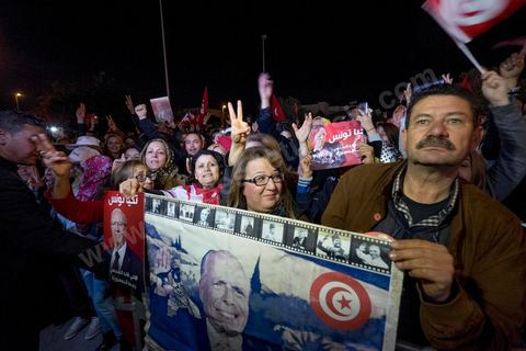 21 décembre 2014 : Militant avec portrait historique de Habib Bourguiba et de Béji Caid Essebsi. Dès la fin du scrutin à 18h, les rumeurs d'une large victoire de Beji Caïd Essebsi, candidat du parti Nidaa Tounes, circulent. Avec 8 à 10 points d'avance selon les sondages, Béji Caid Essebsi remporte les 1ères élections présidentielles libres en Tunisie depuis la révolution de 2011. A cette annonce les militants sont venus nombreux féter la victoire annoncée devant le QG de campagne du parti dans le quartier très huppé des Berges du Lac de Tunis.