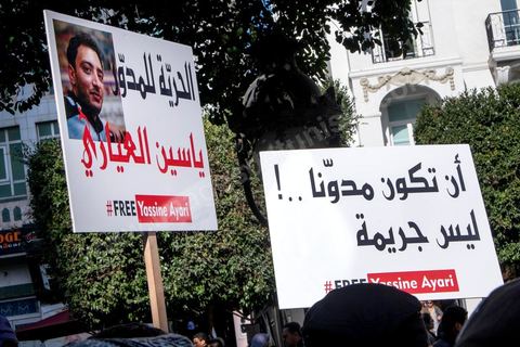 14 janvier 2015 : pancarte de soutien au bloggeur tunisien Yassine Ayari, emprisonnés par l'armée depuis quelques semaines. Les Tunisiens célèbrent sur l'avenue Habib Bourguiba à Tunis le 4ème anniversaire de la révolution tunisienne qui a mené à la chute du président déchu Zine el Abdidine Ben Ali, le vendredi 14 janvier 2011 et son exil vers l’Arabie Saoudite. Entre les nombreux tunisiens venus marcher en famille sous un doux soleil, des regroupements très variés se répartissés l'avenue, famille de martyrs, partisans d'Hizbt Tahrir, d'Ennahdha ou d'El Watan, jeunesse islamiste des LPR, soutien à Sofiane et Nadhir, ...
